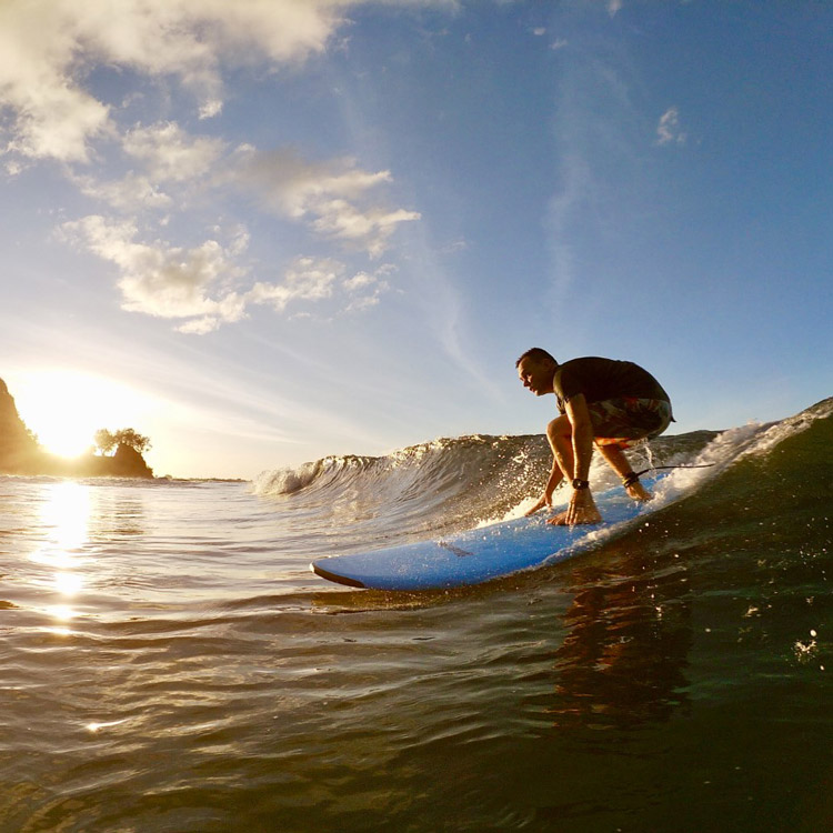 Homme qui surfe en fin de journée à Tahiti