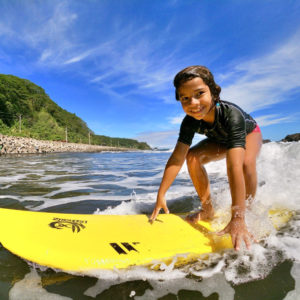 Enfant qui surf ses premières vagues à Tahiti