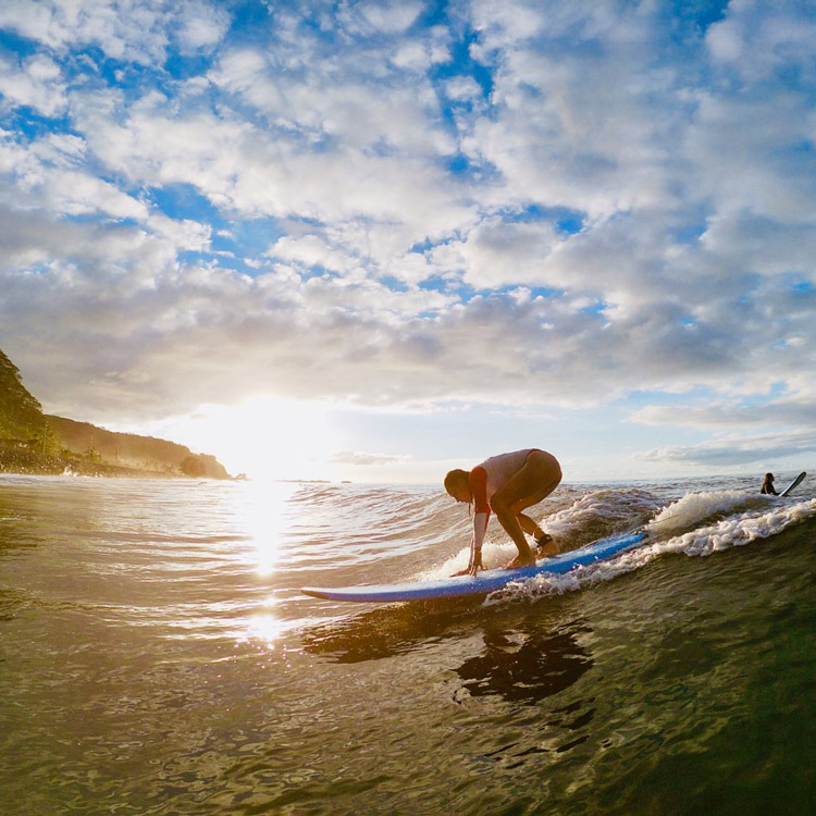 surfeur sur une vague au coucher du soleil à Tahiti
