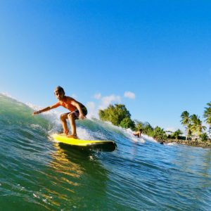 Garçon qui surfe une belle vague à Tahiti